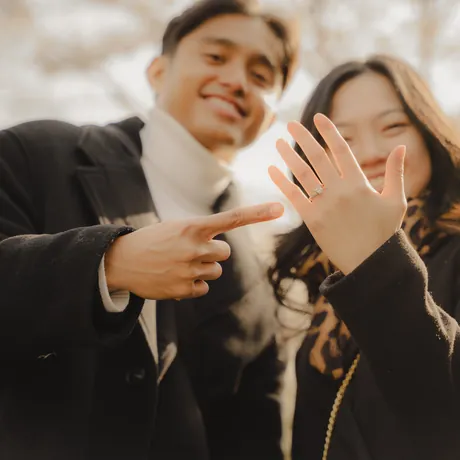 Eden pointing at her new ring, both of them beaming