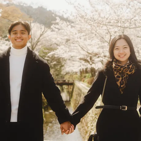 Priam and Eden strolling hand in hand along a cherry-blossom canal