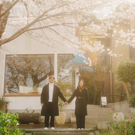 Priam and Eden walking hand in hand under the cherry blossoms